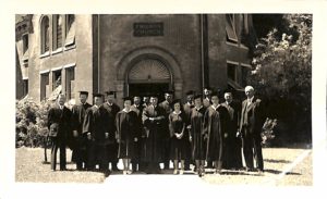 The class of 1940 stand for a photograph in their graduation robes and caps. 