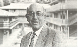 Portrait of Ed Stevens: in a suit, top of head bald, wears glasses. Pictured in front of Willcuts, Beebe, Carey complex. 