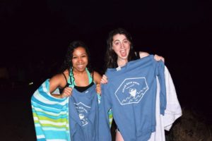 Two students in wet clothes and towels hold up sweatshirts: "Polar Bear Plunge"